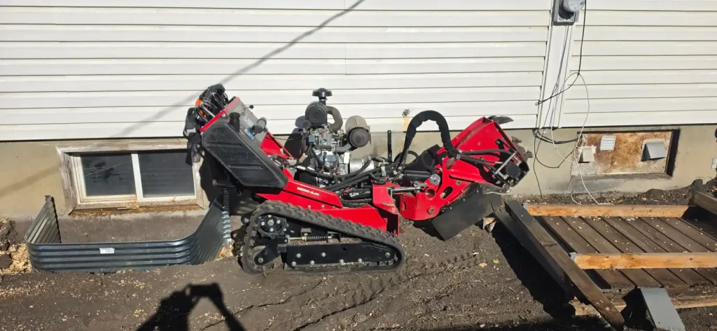 Compact tracked stump grinder beside a Calgary home